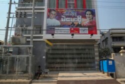 A police officer guards closed doors of National League for Democracy party offices, decorated with pictures of Aung San Suu Kyi, right, flanked by party patron Tin Oo, in Mandalay, Myanmar, Feb. 3, 2021.