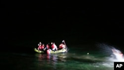 Migrants on board a dinghy try to cross to the nearby Greek island of Kos, from the coastal town of Bodrum, Turkey, early Friday, Aug. 14, 2015. 