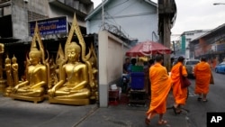 Tiga Bhiksu Budha tengah berjalan melewati toko yang menjual patung-patung Budha di Bangkok, Thailand, 15 Desember 2013 (Foto: dok). Seorang bhiksu dan tiga orang lainnya tewas ditembak serombongan orang-orang tak dikenal di di daerah Mae Lan, provinsi Pattani, Kamis pgi (13/2).