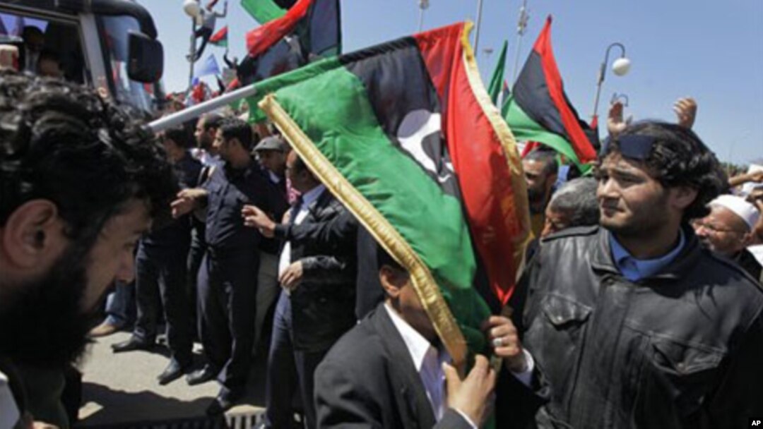 An unidentified African Union delegation official has an opposition flag draped over him as he arrives for meetings with opposition leaders in Benghazi, Libya Monday, April 11, 2011.