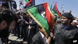 An unidentified African Union delegation official has an opposition flag draped over him as he arrives for meetings with opposition leaders in Benghazi, Libya Monday, April 11, 2011.