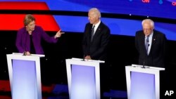 Democratic presidential candidate Sen. Elizabeth Warren, D-Mass., left, speaks to Sen. Bernie Sanders, I-Vt., right as former Vice President Joe Biden watches Tuesday, Jan. 14, 2020, during a Democratic presidential primary debate.