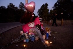 FILE - Paramedic Rebecca Mackowiak passes a makeshift memorial for Gilroy Garlic Festival shooting victims outside the festival grounds, July 29, 2019, in Gilroy, Calif.