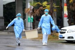 FILE - Medical staff carry a box as they walk at the Jinyintan hospital, where the patients with pneumonia caused by the new strain of coronavirus are being treated, in Wuhan, Hubei province, China, Jan. 10, 2020.