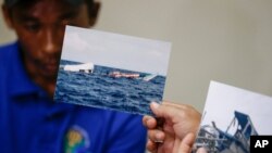 Photos of the damaged Filipino fishing vessel F/B Gimver 1 is shown next to one of its crew Richard Blaza during a press conference by Department of Agriculture Secretary Emmanuel Pinol in metropolitan Manila, Philippines, June 17, 2019.