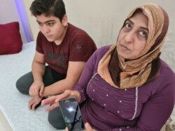 Najma, 50 and her son Mohammed, 14, with a video taken by a man on their boat who hid his phone in his baby's blanket while others were reportedly confiscated, pictured on Aug. 25, 2020 in Istanbul. (Heather Murdock/VOA)