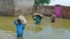 Una familia desplazada por las inundaciones lleva sus pertenencias mientras caminan por las áreas inundadas después de las fuertes lluvias monzónicas en Sohbatpur, en el distrito de Jaffarabad, provincia de Baluchistán, el 19 de agosto de 2024.