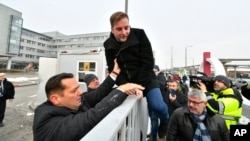 Parliamentary deputy of the oppositional Hungarian Socialist Party MSZP Zsolt Molnar, left, helps MSZP deputy Tamas Harangozo climb the fence of the public broadcaster MTVA in Budapest, Hungary, Dec. 17, 2018.