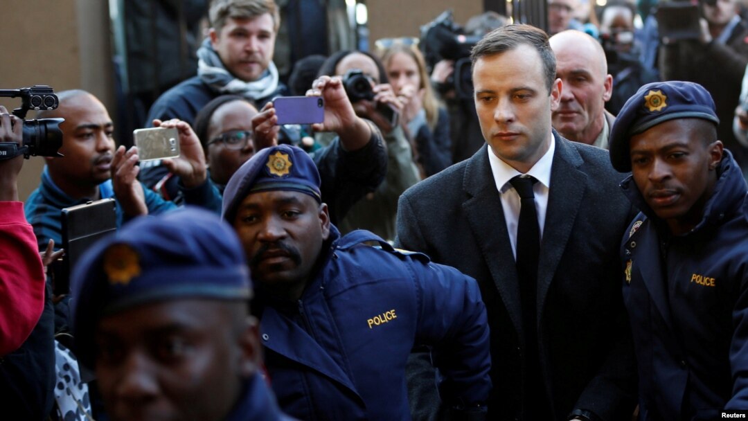 Pelari peraih medali emas Paralimpik, Oscar Pistorius dikawal oleh perwira polisi saat tiba untuk pembacaan hukuman yang akan diterimanya terkait kasus pembunuhan pacarnya, Reeva Steenkamp, di Pengadilan Tinggi Pretoria di Afrika Selatan, 6 Juli 2016. (Foto:dok)