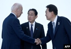 (FILES) (Kiri ke Kanan) Presiden AS Joe Biden, Perdana Menteri Jepang Kishida Fumio, dan Presiden Korea Selatan Yoon Suk Yeol saling menyapa menjelang pertemuan trilateral selama KTT Pemimpin G7 di Hiroshima pada 21 Mei 2023. (Brendan SMIALOWSKI / AFP)