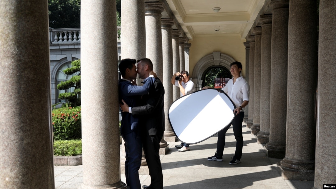 Lin Chinxuan, right, holds a reflector as Austin Haung, 32, photographs Kao Shaochun, left, and John Sugden during their pre-wedding photoshoot in Taipei, Taiwan, Nov. 11, 2018. Chinxuan and Haung are a couple and together they run Hiwow studio photographing LGBTQ couples.