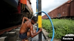 Prakash Nagre washes himself at Aurangabad railway station, Aurangabad India, Aug. 2, 2019. 