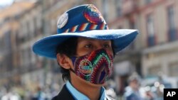 Un músico callejero boliviano usa una mascarilla fabricada por mujeres de ese país en medio de la pandemia que ya ha llevado a los hospitales a su límite de capacidad.
