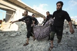Syrian men carry a victim after a reported Russian airstrike on a popular market in the village of Balyun in Syria's northwestern Idlib province, Dec. 7, 2019.