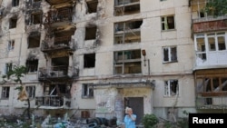一位當地婦女站在北頓涅茨克嚴重破壞的居民樓前。