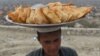 An Afghan samosa vendor looks on as he waits for customers at Wazir Akbar Khan hilltop overlooking Kabul on March 26, 2019.