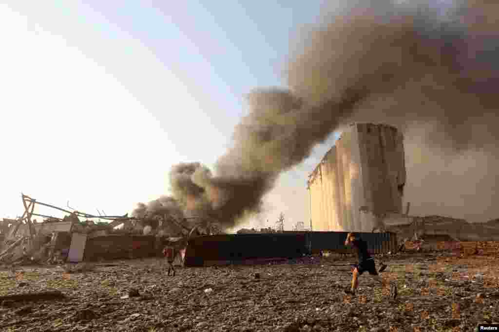 A man runs as smoke rises at the site of an explosion in Beirut, Lebanon, Aug. 4, 2020. 