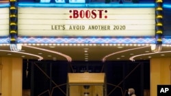 FILE - A man walks underneath the marquee of the Alex Theatre in Glendale, Calif., which bears a message urging people to get COVID-19 vaccine booster shots, Monday, Jan. 24, 2022.