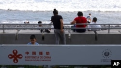 FILE - A sign reading in Spanish 'Assistance from China, for a shared future' is part of the remodeling work in the area of the boardwalk on the pier in La Libertad, El Salvador, June 18, 2021.