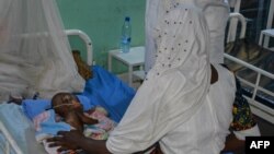 Une mère s'occupe de son enfant malnutri au service de pédiatrie d'un hôpital de Ndjamena, Tchad, le 15 février 2022.