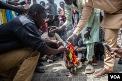 Des manifestants brûlent un drapeau arc-en-ciel lors d'un rassemblement anti-gay à Dakar, au Sénégal, le 20 février 2022. (Annika Hammerschlag/VOA)