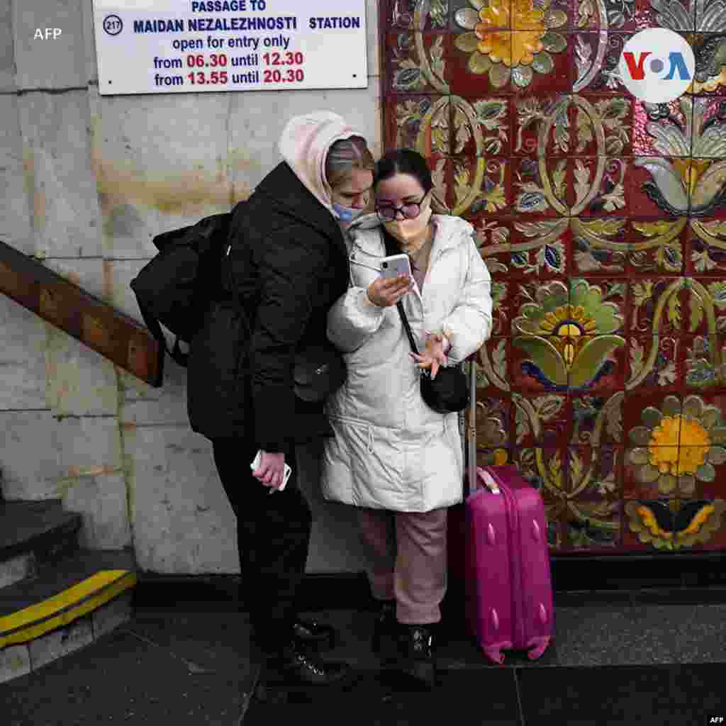 Varias personas, algunas con bolsas y maletas, caminan en una estación de metro en Kiev ante temor de un conflicto armado.