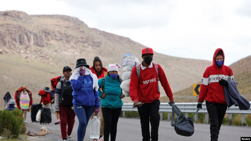 Migrantes venezolanos caminan por una carretera después de cruzar la frontera en las tierras altas entre Bolivia y Chile, en Colchane, Chile 15 de febrero de 2022.