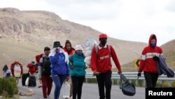 Migrantes venezolanos caminan por una carretera después de cruzar la frontera en las tierras altas entre Bolivia y Chile, en Colchane, Chile 15 de febrero de 2022. 