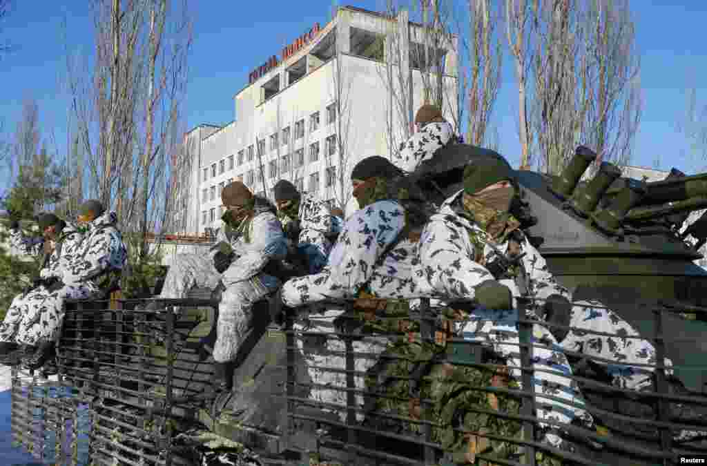 Miembros del servicio viajan encima de un vehículo blindado de transporte de personal durante los ejercicios tácticos realizados por la Guardia Nacional de Ucrania.