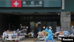 2022 年 2 月 17 日在香港爆發新冠病毒病後，穿著個人防護設備的醫務人員在醫院外設立的臨時治療區的病床上工作 （路透社照片） 