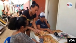 La fila de mesas es larga en esta calle del archipiélago de Los Roques donde los lugareños se enfrascan en su diaria Lotería tradicional.