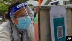A woman wearing protective mask scans a QR code before queuing up to get tested for the coronavirus at a temporary testing center for COVID-19 in Hong Kong, Feb. 24, 2022. 