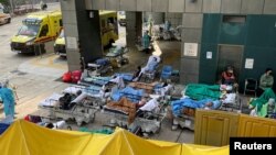 Patients wearing face masks lie in bed at a makeshift treatment area outside a hospital, following the COVID-19 outbreak in Hong Kong, Feb. 16, 2022. 