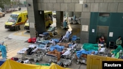 Patients wearing face masks lie in bed at a makeshift treatment area outside a hospital, following the COVID-19 outbreak in Hong Kong, Feb. 16, 2022. 