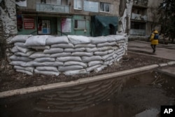 FILE - A journalist passes by a shelter near an apartment building after shelling by Russia-backed separatists in the town of Novoluhanske, Luhansk region, eastern Ukraine, Feb. 19, 2022.
