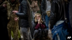 A woman reacts as she waits for a train trying to leave Kyiv, Feb. 24, 2022, as Russia launched its invasion of Ukraine. (AP Photo/Emilio Morenatti)