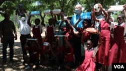 Students at Sekeni Primary School in Chikwawa district hold up educational materials and other supplies they received from UNICEF. (Lameck Masina/VOA)