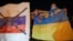 Ukrainians hold up their country's flag, right, as they attend a patriotic action 'Mariupol is Ukraine' in Mariupol, Ukraine, Feb. 22, 2022.