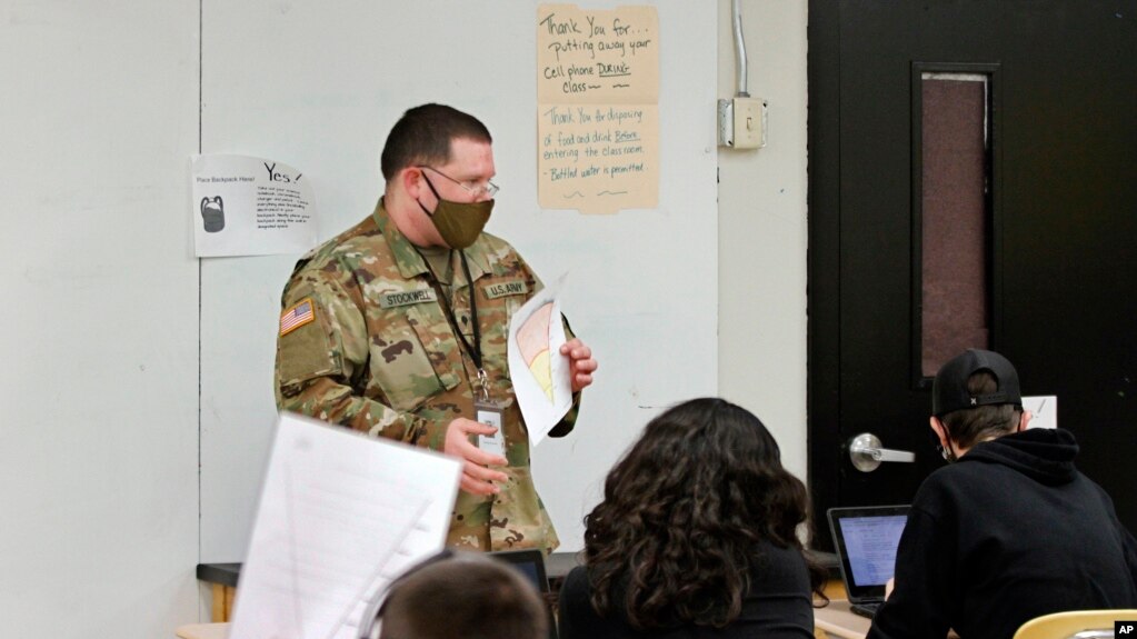 Substitute teacher and New Mexico Army National Guard specialist Michael Stockwell substitute holds up a geology assignment while teaching students at Alamogordo High School.