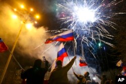 People wave Russian national flags celebrating the recognizing the independence in the center of Donetsk, the territory controlled by pro-Russian militants, eastern Ukraine, Feb. 21, 2022.