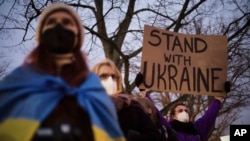 A man holds a poster in support of Ukraine as he attends a demonstration near the Russian embassy to protest against the escalation of the tension between Russia and Ukraine in Berlin, Germany, Feb. 22, 2022. 