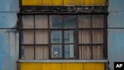 A woman looks out of the window of a balcony in Sievierodonetsk, in the Luhansk region, eastern Ukraine, Feb. 18, 2022.