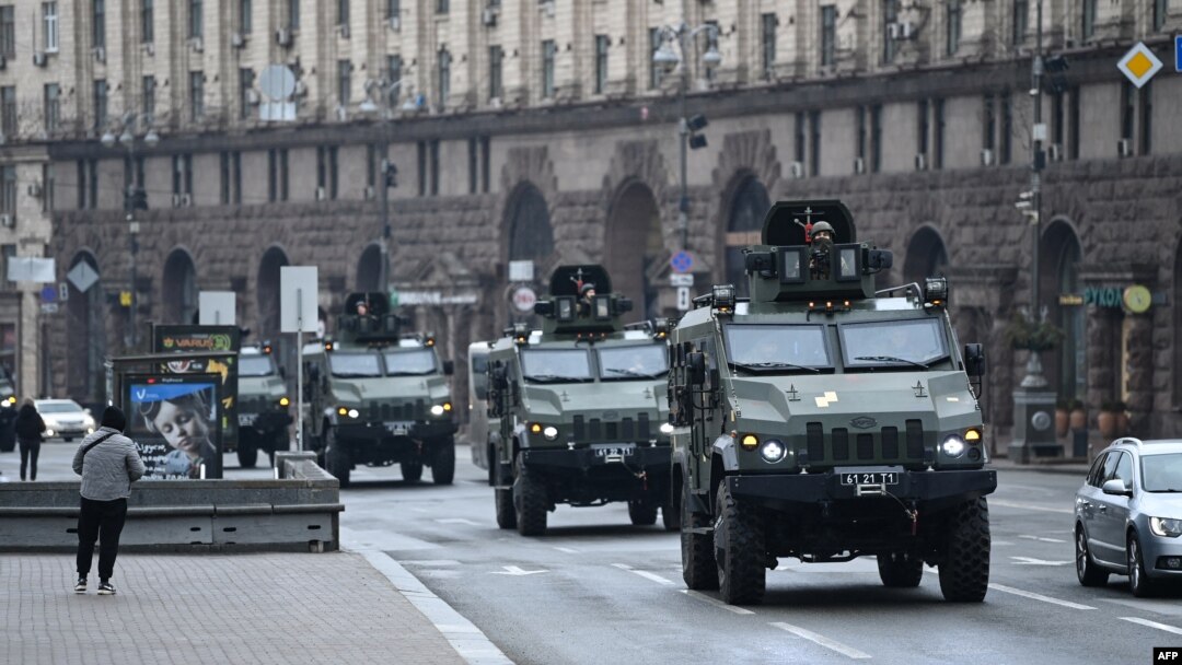 Ukrainian military vehicles move past Independence Square in central Kyiv, Feb. 24, 2022, after cities were hit with what Ukrainian officials said were Russian missile strikes and artillery.