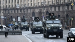 Ukrainian military vehicles move past Independence Square in central Kyiv, Feb. 24, 2022, after cities were hit with what Ukrainian officials said were Russian missile strikes and artillery.