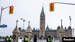 Polisi berjalan di sepanjang Wellington Street untuk mengusir truk dan pendukung terakhir yang menduduki pusat kota, setelah tiga minggu menggelar aksi protes terhadap mandat vaksin COVID-19 dimulai di Ottawa, Ontario, Kanada, 20 Februari, 2022. (REUTERS/Carlos Osorio)