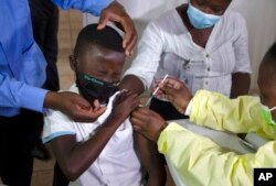 FILE - A child gets a vaccine against COVID-19 in Diepsloot Township near Johannesburg, October 21, 2021.