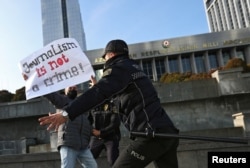 FILE - Police officers restrain a protester during a rally in front of the Parliament building in Baku, Azerbaijan, Dec. 28, 2021.