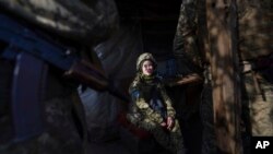 A Ukrainian soldier talks with her comrades sitting in a shelter at the line of separation between Ukraine-held territory and rebel-held territory near Svitlodarsk, eastern Ukraine, Feb. 23, 2022. 