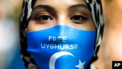 FILE - A woman wears a face mask reading 'Free Uyghurs' as she attends a protest during the visit of Chinese Foreign Minister Wang Yi in Berlin, Sept. 1, 2020. 