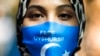 FILE - A woman wears a face mask reading 'Free Uyghurs' as she attends a protest during the visit of Chinese Foreign Minister Wang Yi in Berlin, Sept. 1, 2020. 